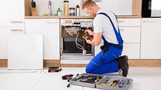 A dishwasher being repaired by a professional